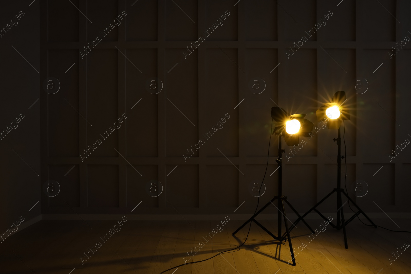 Photo of Bright yellow spotlights near wall in dark room, space for text