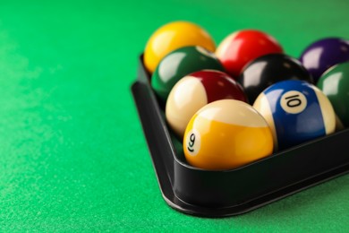 Photo of Billiard balls in triangle rack on green table, closeup. Space for text