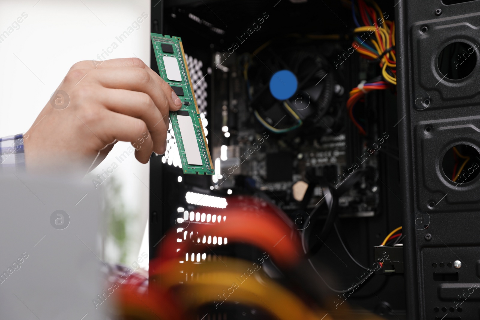 Photo of Male technician putting RAM chip into system unit, closeup. Computer repair