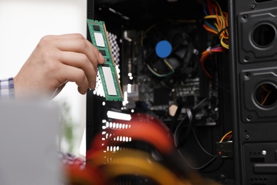 Photo of Male technician putting RAM chip into system unit, closeup. Computer repair