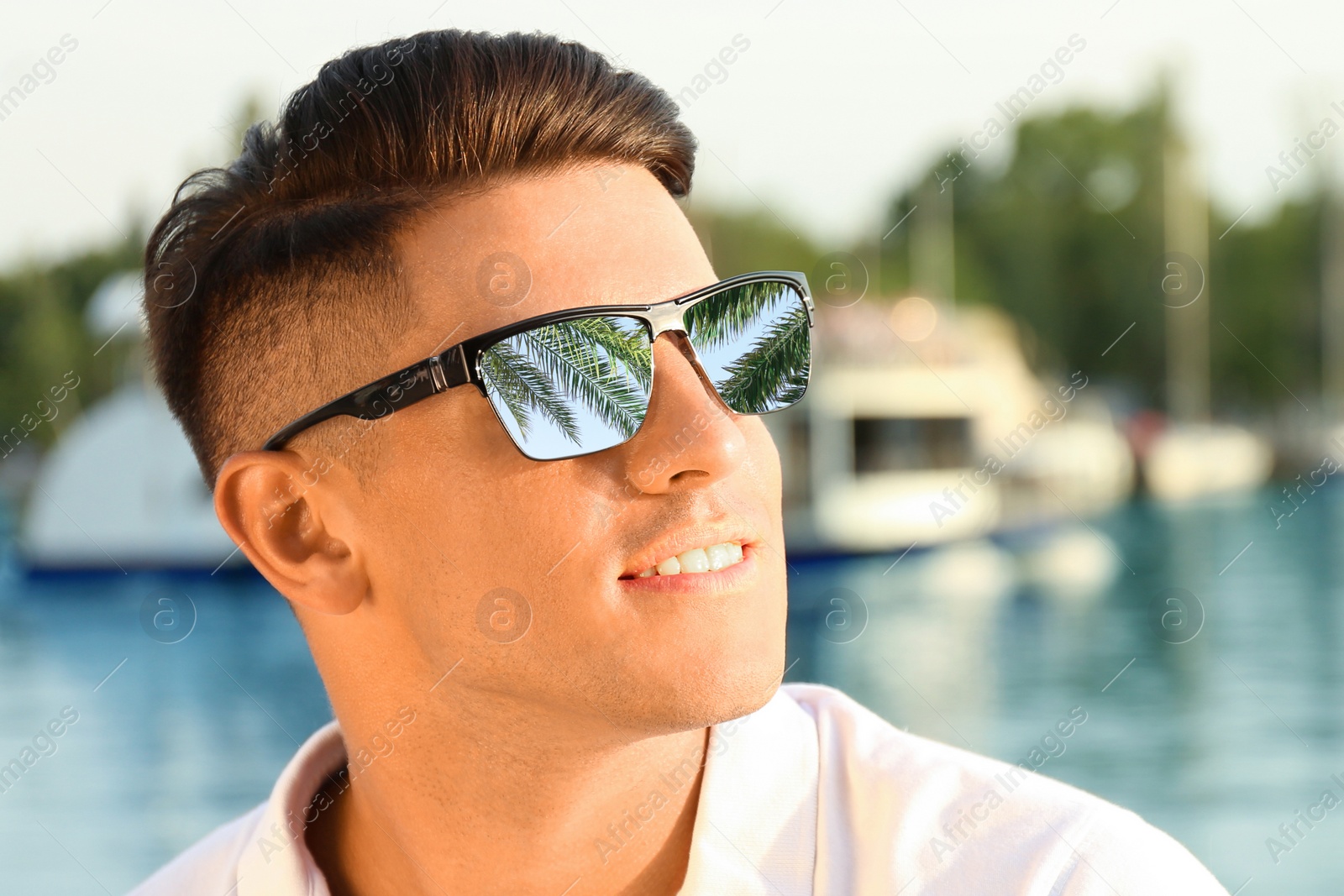 Image of Happy man on vacation. Green palm leaves mirroring in his sunglasses