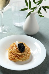 Photo of Tasty spaghetti with tomato sauce and black caviar served on table, closeup. Exquisite presentation of pasta dish