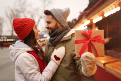 Photo of Lovely couple at winter fair, focus on Christmas present