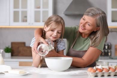 Photo of Happy grandmother with her granddaughter cooking together in kitchen