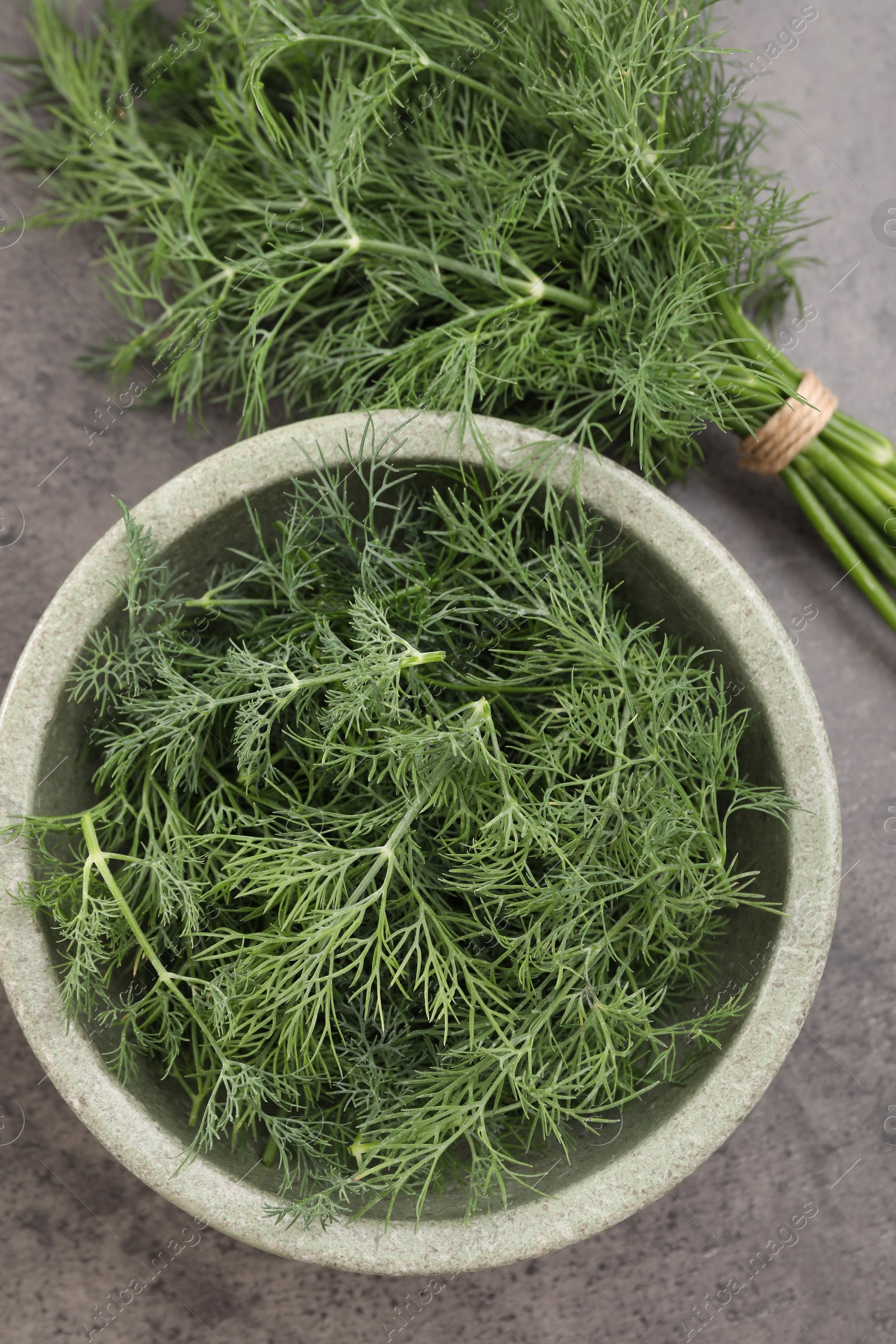 Photo of Bowl of fresh dill on grey table, flat lay
