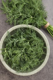 Photo of Bowl of fresh dill on grey table, flat lay