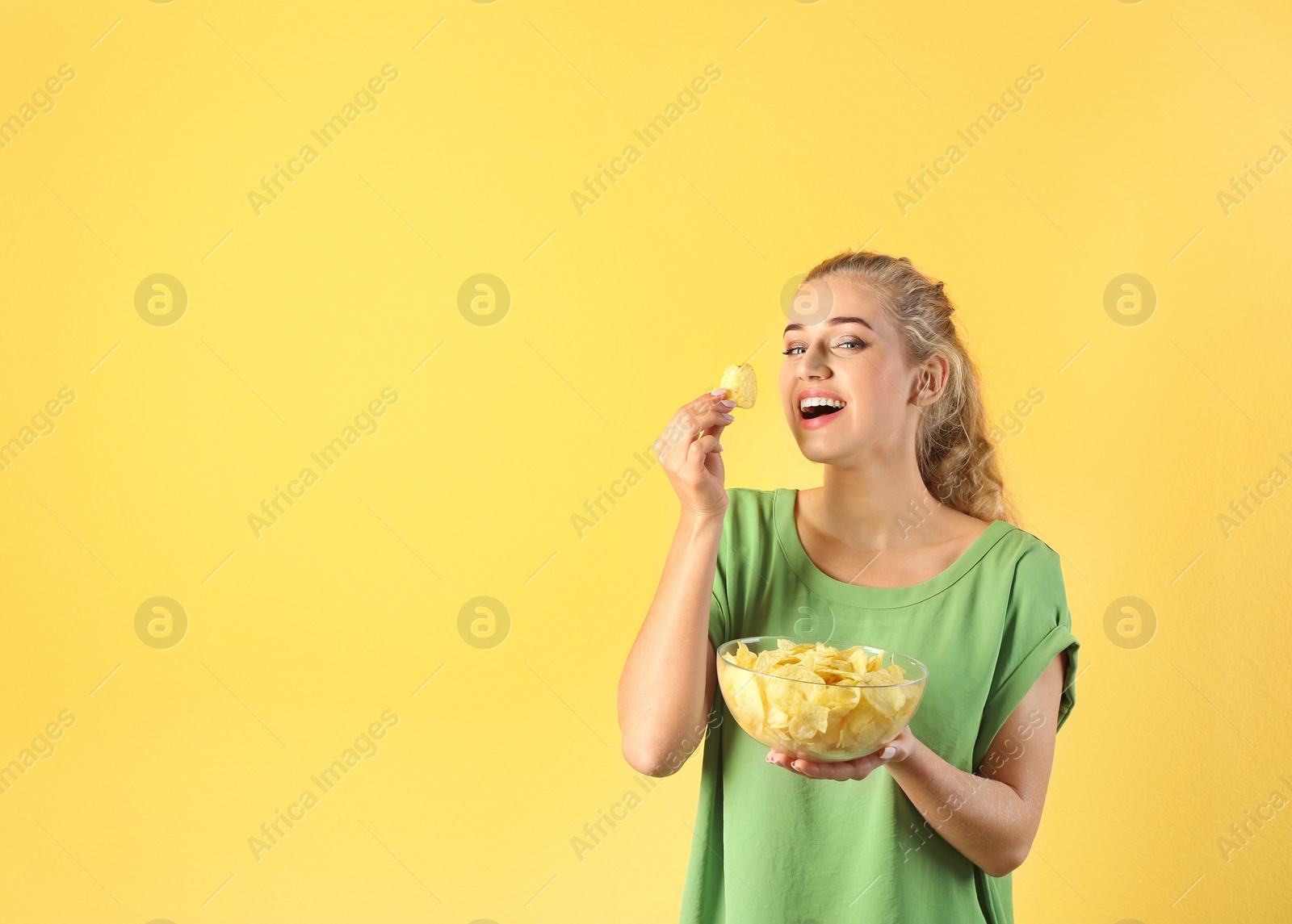 Photo of Woman eating potato chips on color background. Space for text