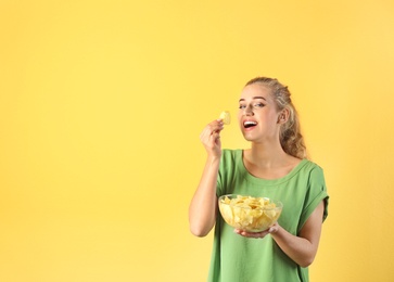 Photo of Woman eating potato chips on color background. Space for text