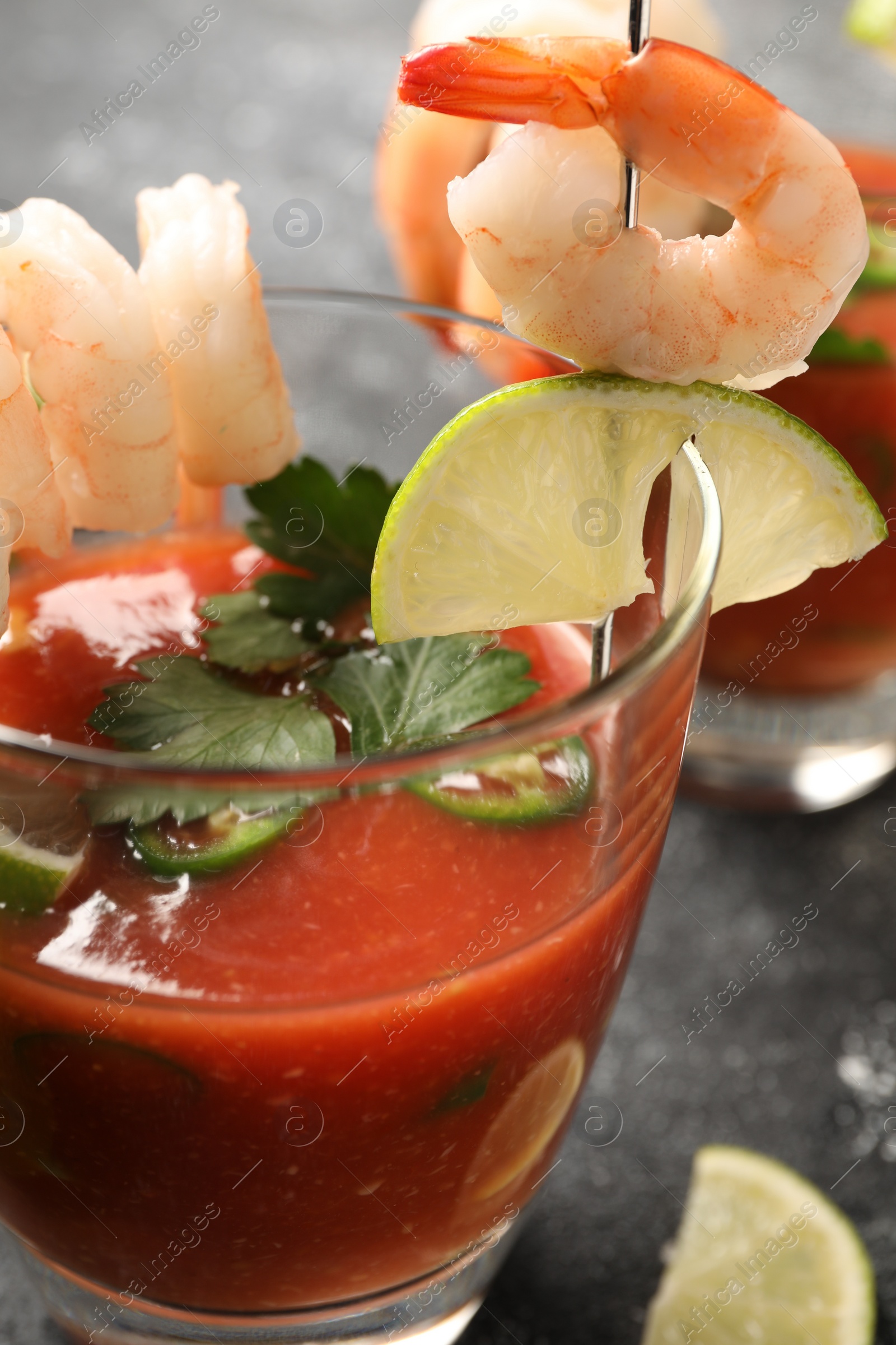 Photo of Tasty shrimp cocktail with sauce in glass and lime on grey table, closeup