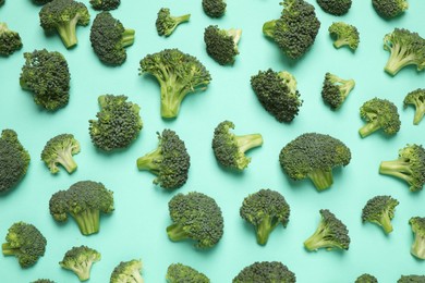 Photo of Fresh tasty broccoli on turquoise background, flat lay