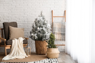 Stylish interior with beautiful Christmas tree near white brick wall