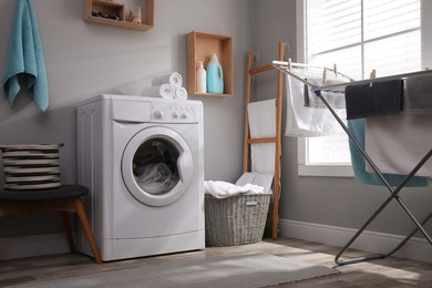 Laundry room interior with modern washing machine near light wall