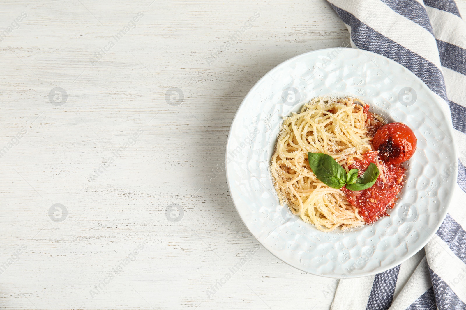 Photo of Tasty pasta and napkin on white wooden table, flat lay. Space for text