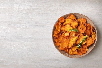 Photo of Plate of sweet potato chips on light table, top view. Space for text