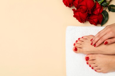 Photo of Woman with stylish red toenails after pedicure procedure and rose flowers on beige background, top view. Space for text