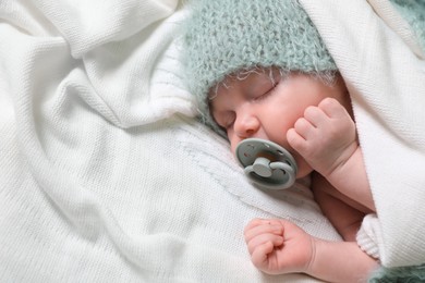 Photo of Cute newborn baby with pacifier sleeping on white blanket, space for text
