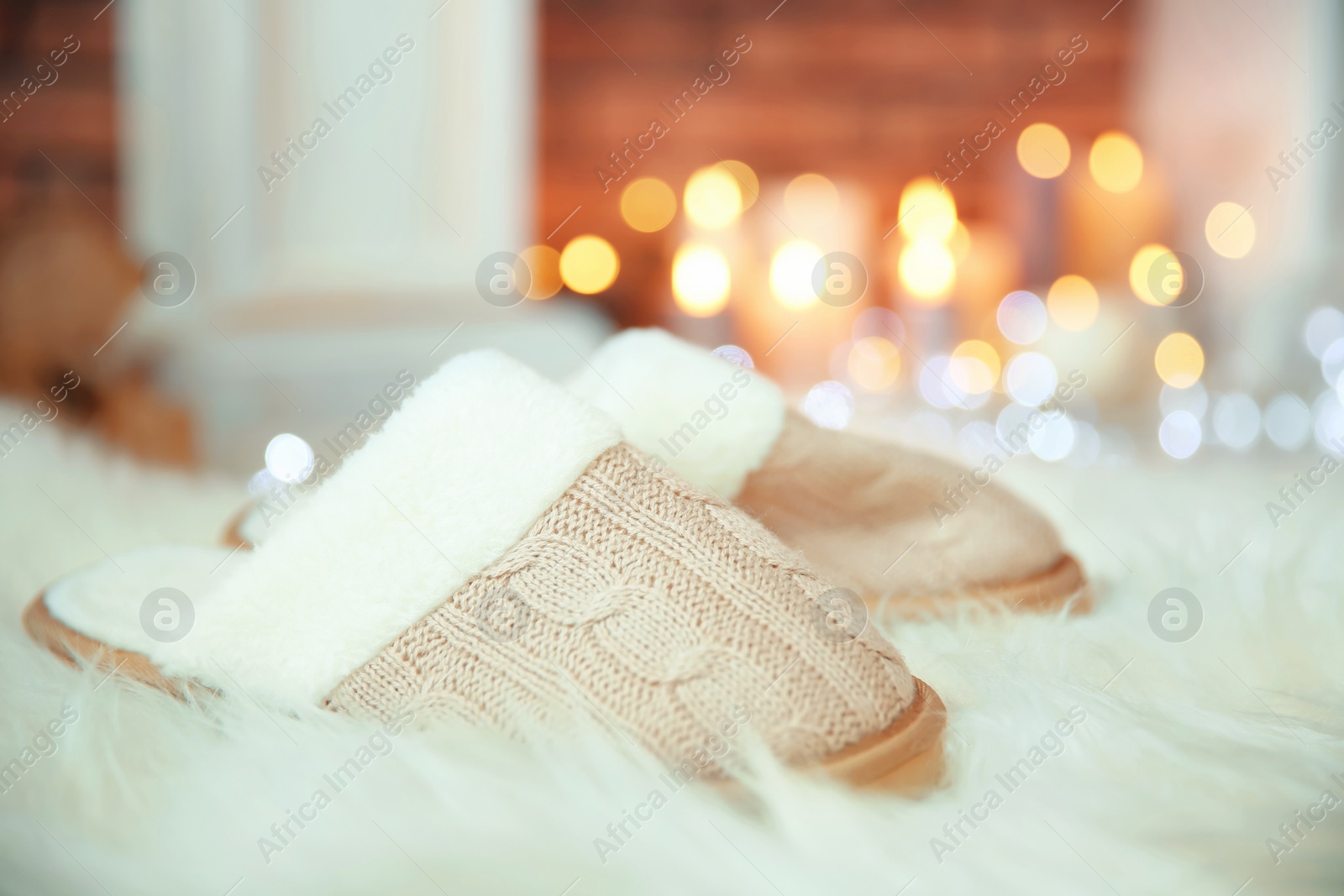 Photo of Soft slippers, fuzzy rug and blurred Christmas lights on background