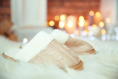 Photo of Soft slippers, fuzzy rug and blurred Christmas lights on background