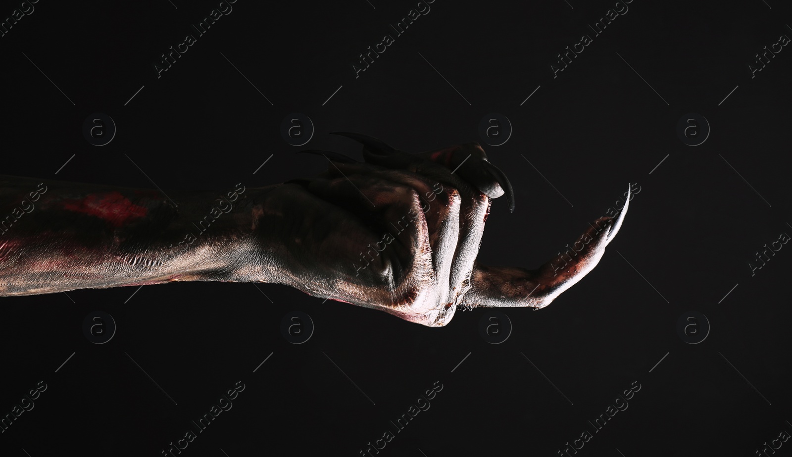 Photo of Scary monster on black background, closeup of hand. Halloween character