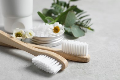 Photo of Bamboo toothbrushes, flowers and sea salt on light grey table, closeup