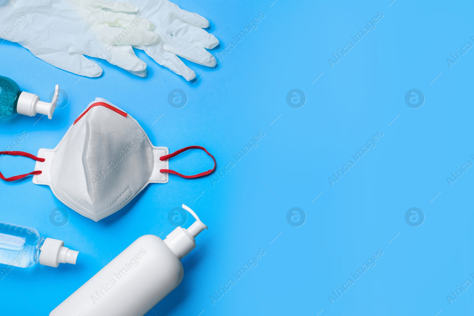 Photo of Medical gloves, respiratory mask and hand sanitizers on light blue background, above view. Space for text