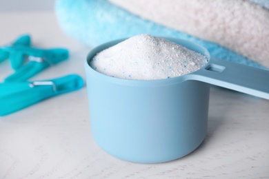 Photo of Measuring spoon of laundry powder near towels and clothespins on table