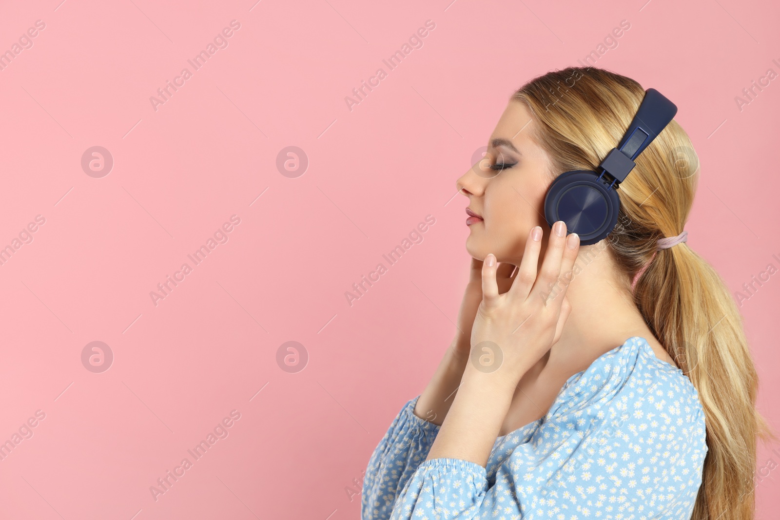 Photo of Beautiful woman in headphones enjoying music on pink background. Space for text