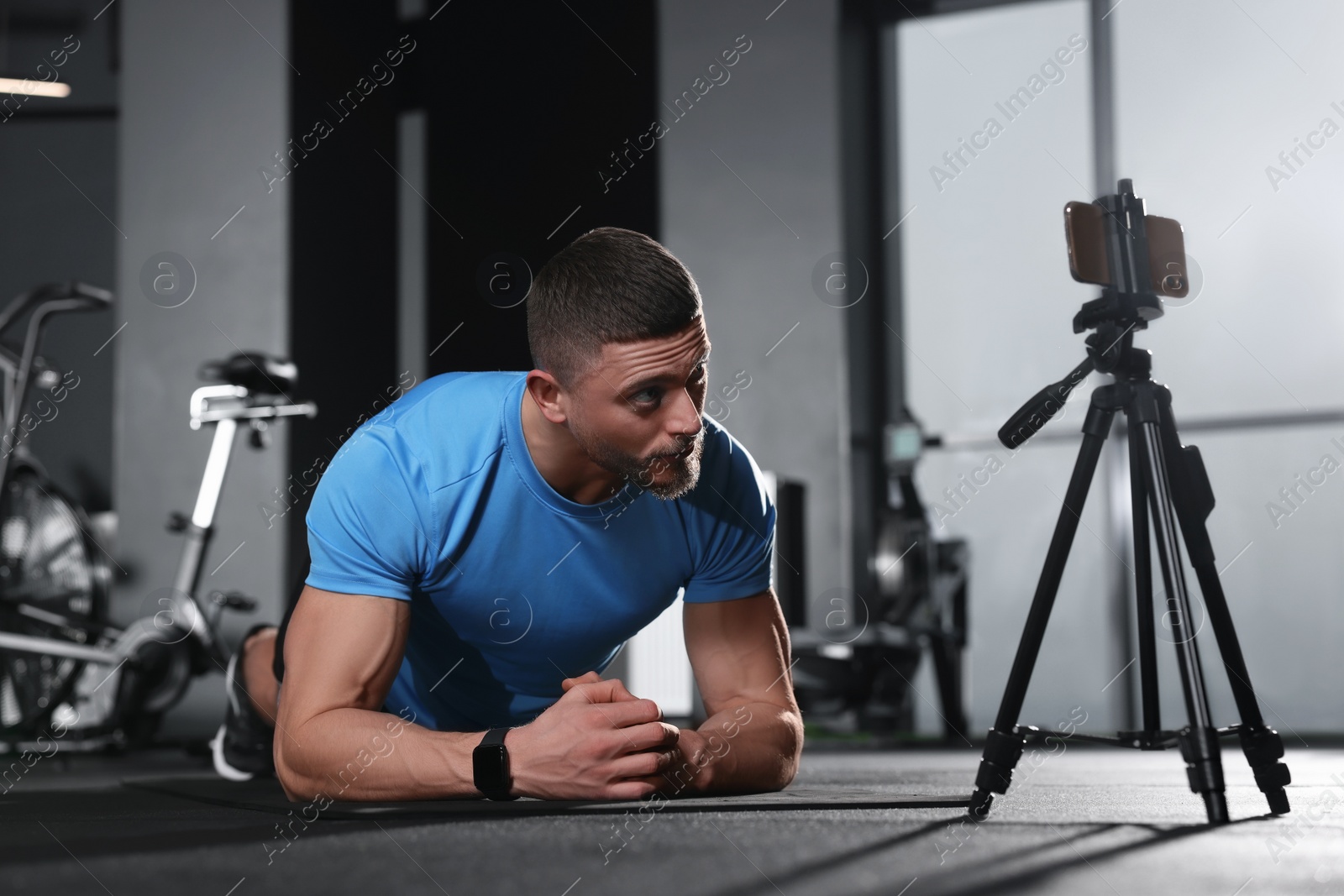 Photo of Trainer streaming online workout with phone at gym