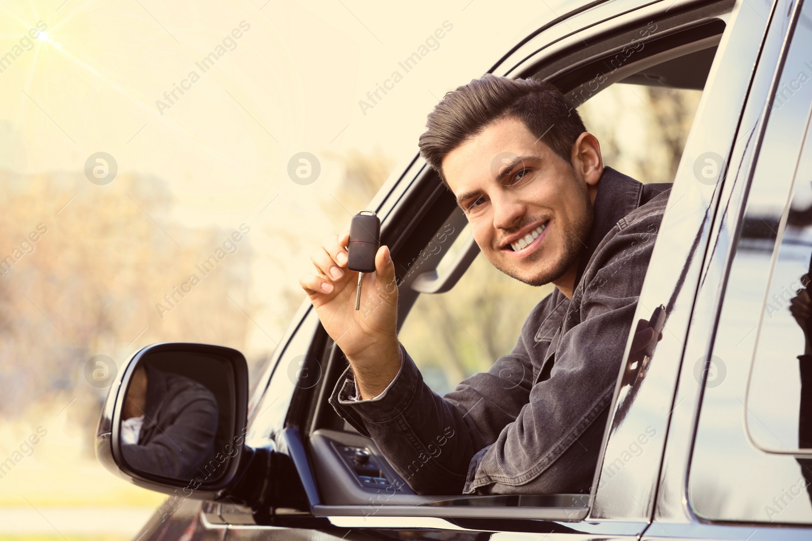 Image of Man with key sitting in car outdoors. Buying new auto