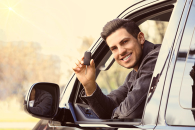 Image of Man with key sitting in car outdoors. Buying new auto