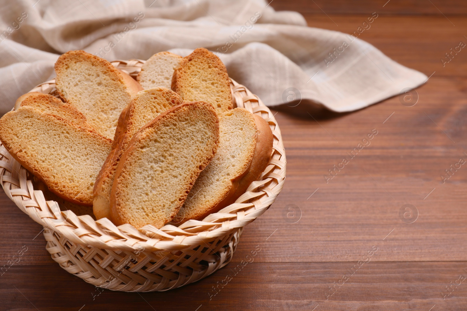 Photo of Hard chuck crackers in wicker basket on wooden table. Space for text