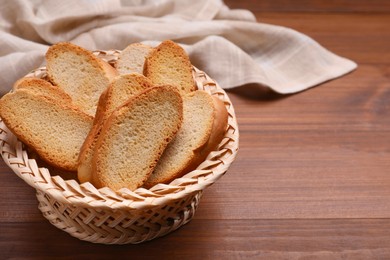 Photo of Hard chuck crackers in wicker basket on wooden table. Space for text