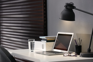 Modern laptop and stationery on table in office