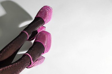 Photo of Woman wearing pink high heeled shoes with platform and square toes on light grey background, closeup. Space for text