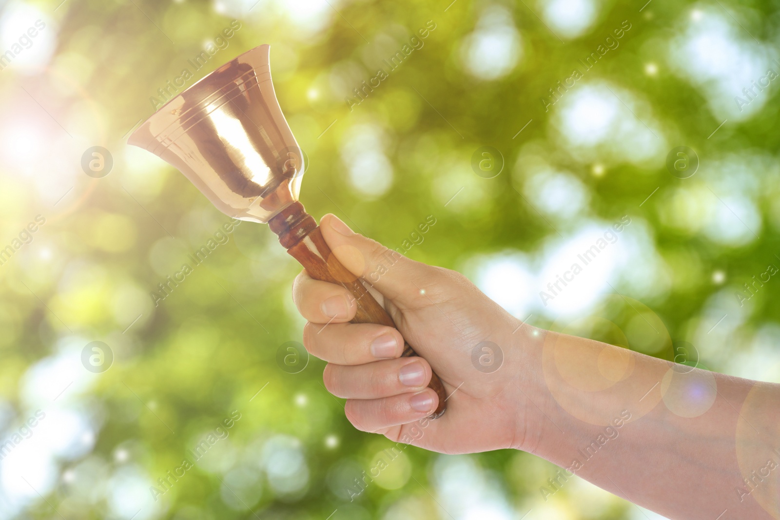 Image of Woman with school bell outdoors, closeup. Bokeh effect