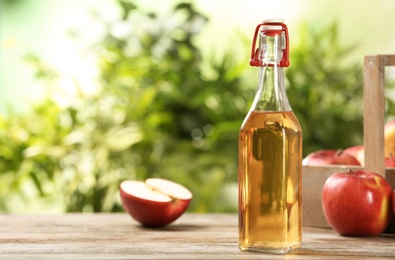 Photo of Composition with bottle of apple vinegar on table. Space for text