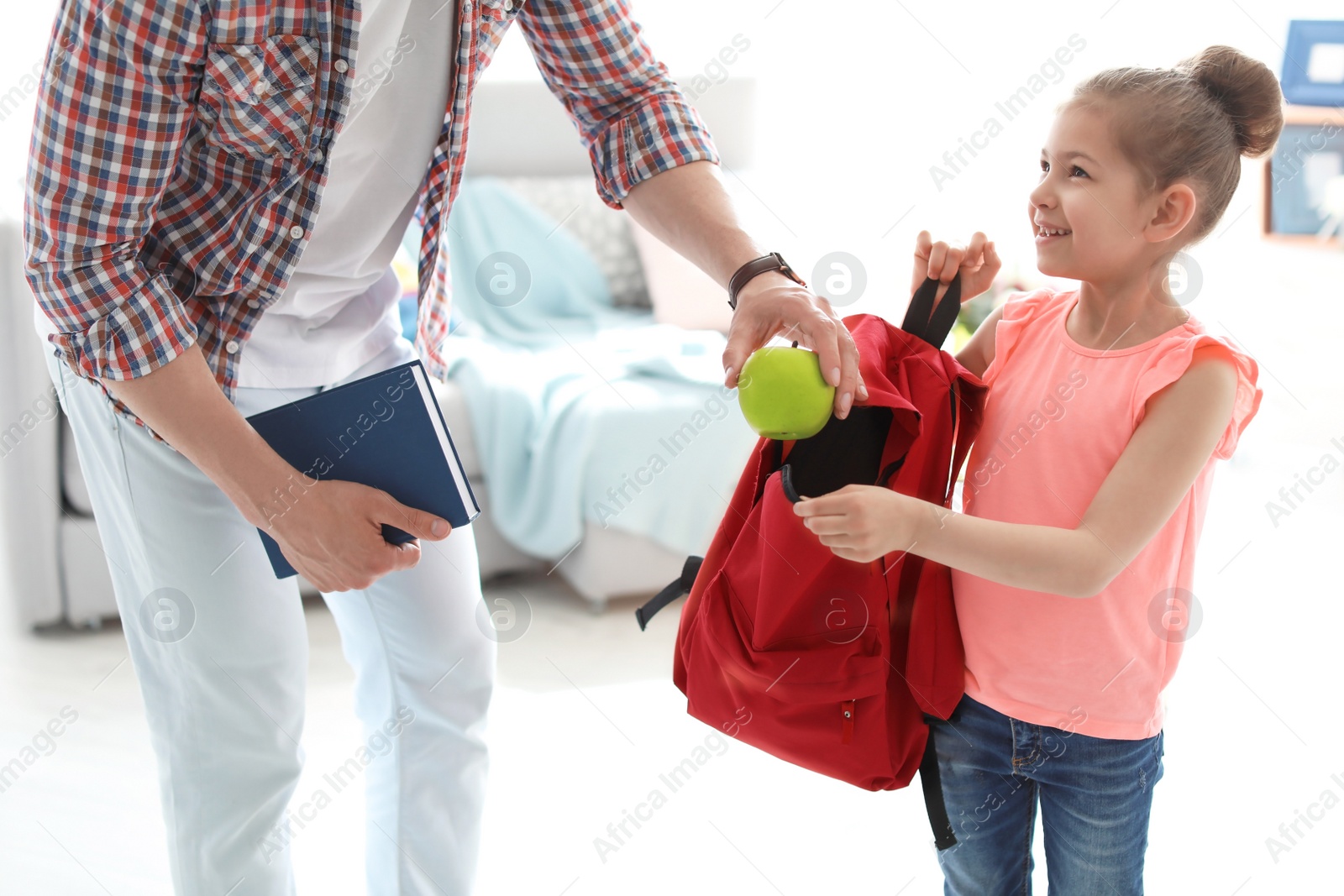 Photo of Young man helping his little child get ready for school at home