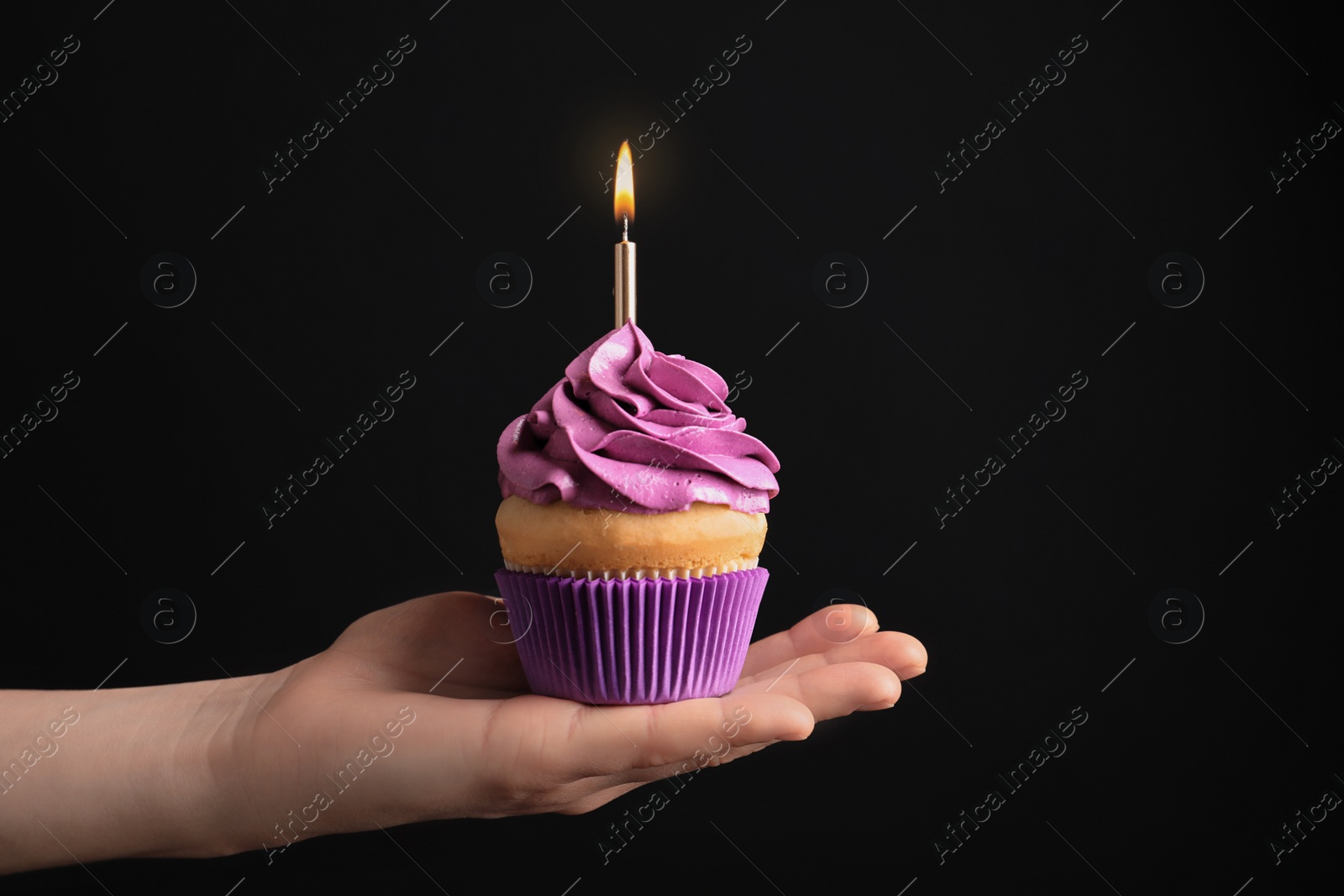 Photo of Woman holding birthday cupcake on black background