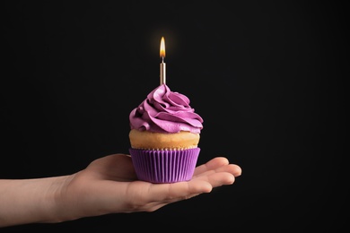 Woman holding birthday cupcake on black background