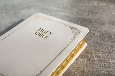 Old hardcover Bible on grey table, closeup. Religious book