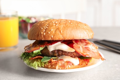 Photo of Plate with tasty bacon burger on table