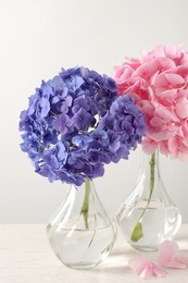 Beautiful bright hortensia flowers on white wooden table against light background