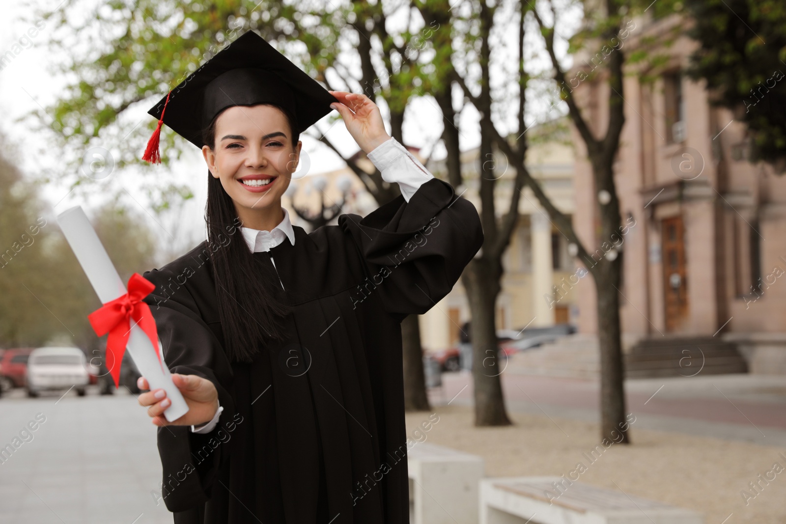Photo of Happy student with diploma after graduation ceremony outdoors. Space for text
