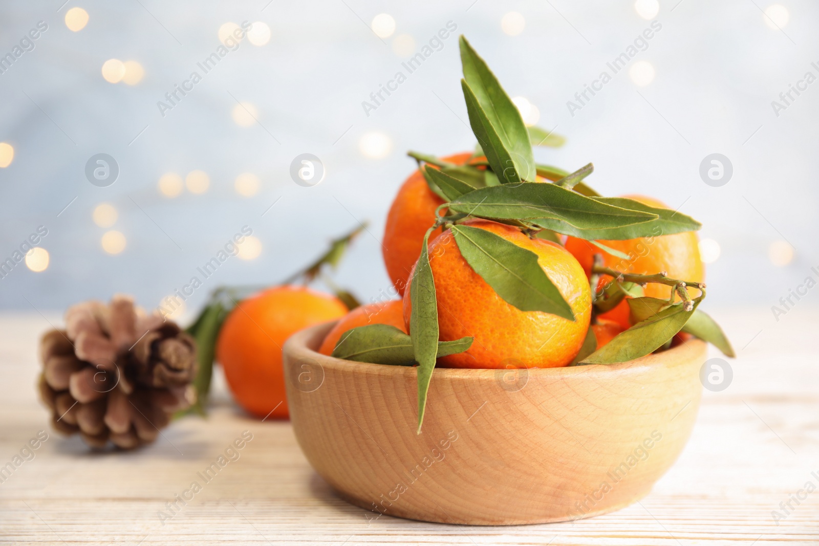 Photo of Bowl with ripe tangerines and blurred Christmas lights on background. Space for text