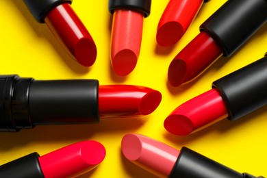 Photo of Many bright lipsticks on yellow background, flat lay