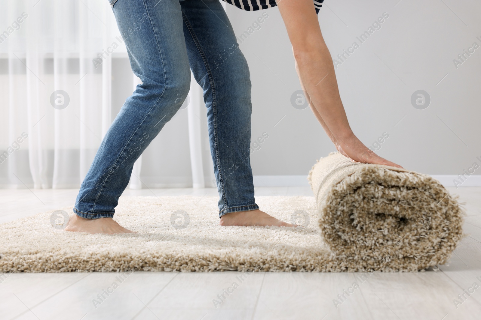 Photo of Man unrolling carpet on floor in room, closeup