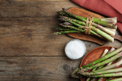 Photo of Fresh raw asparagus on wooden table, flat lay. Space for text