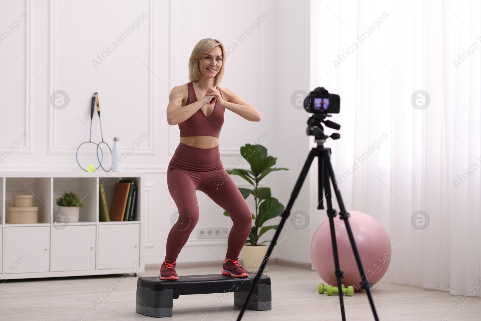 Photo of Smiling sports blogger recording fitness lesson with camera at home