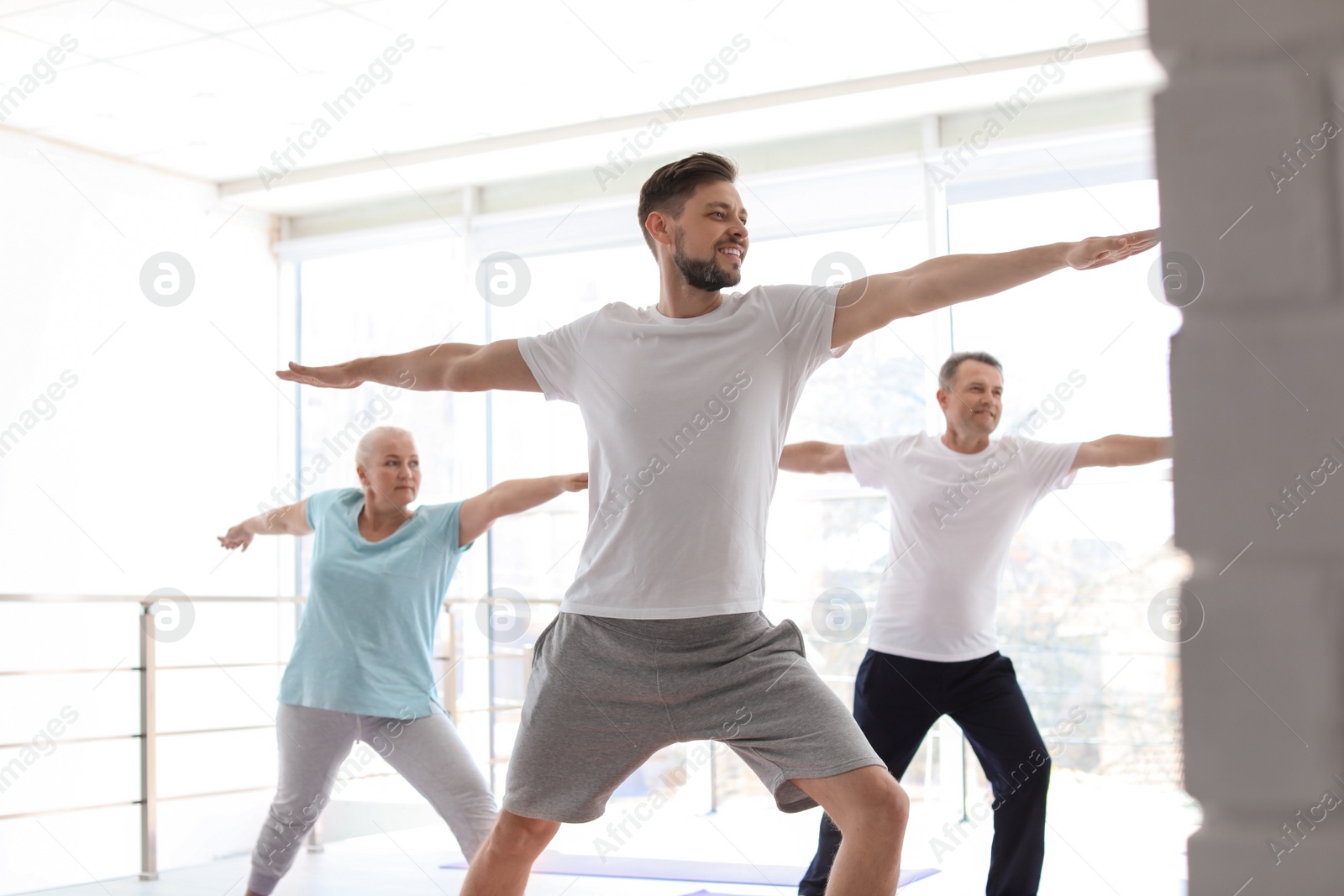 Photo of Group of people in sportswear practicing yoga indoors