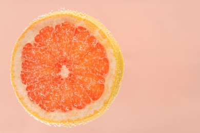 Photo of Slice of grapefruit in sparkling water on light pink background. Citrus soda